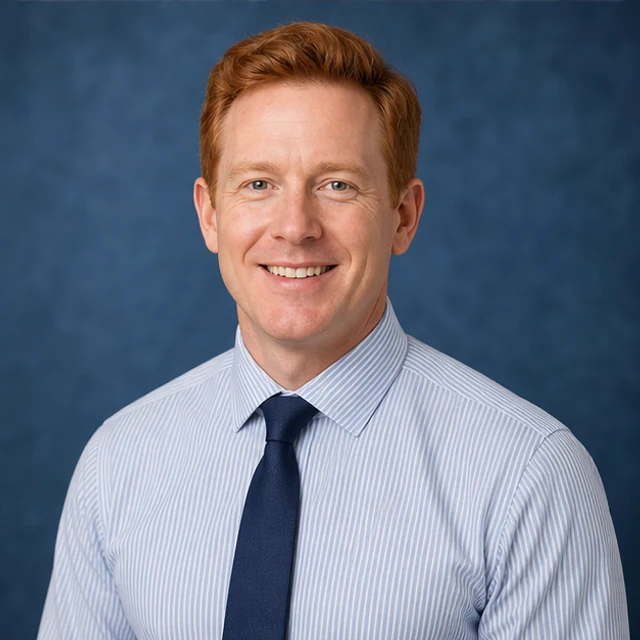 White man with red hair in smart casual shirt and tie on blue studio background - Professional Headshots AI profile photo